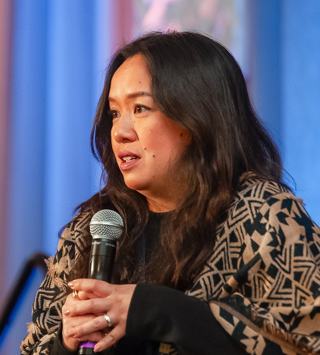 Karla Gregorio speaking at a convening, holding a microphone